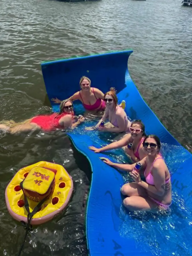 Friends relaxing on the floating lily-pad mat beside the boat at a Fort Lauderdale sandbar