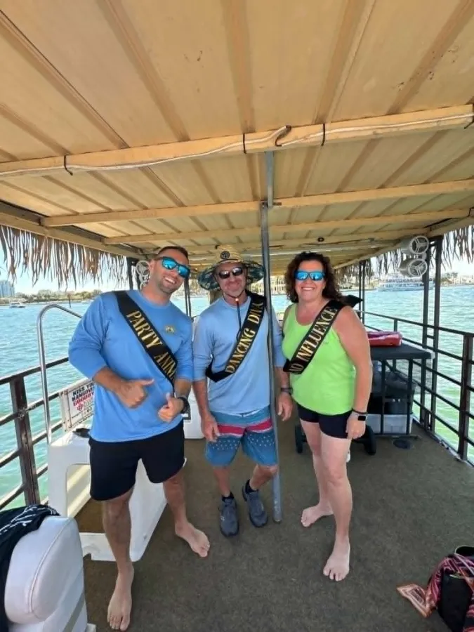 Guests in party sashes celebrating under the tiki roof aboard Breezy Tiki